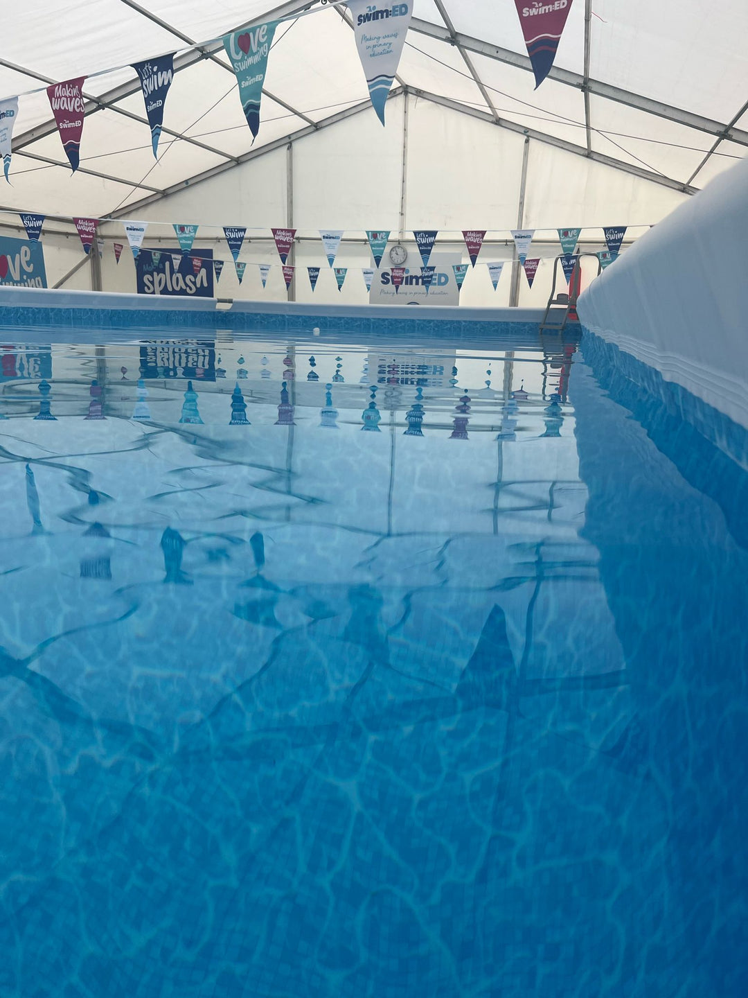 Indoor portable swimming pool with blue water set up in a Wiltshire Primary School. School swimming programme used for primary school swimming lessons.